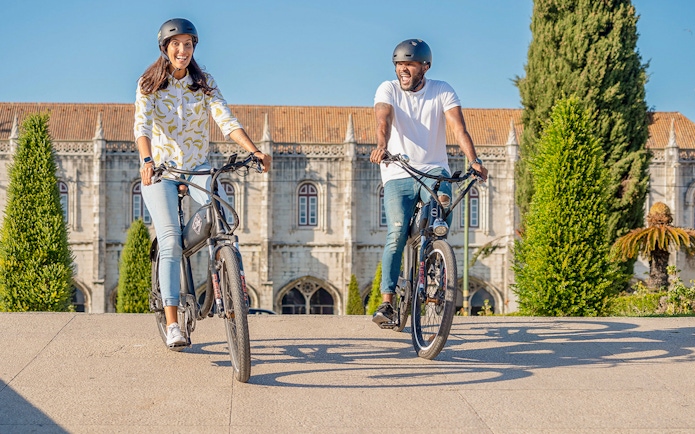 Cyclists enjoying Lisbon e-bike tour near historic Belém landmark.