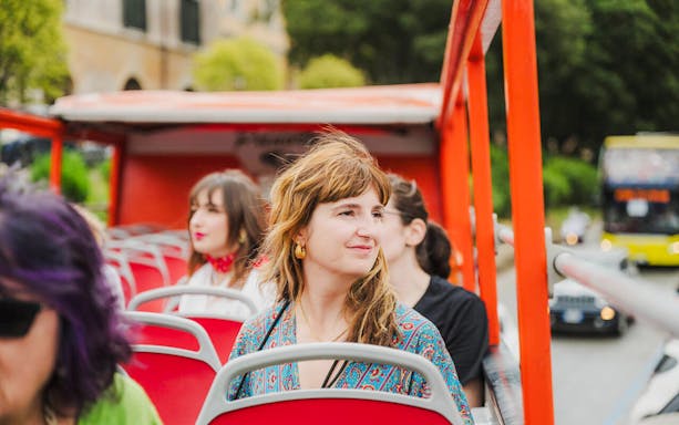 Sightseers on an open-top bus tour in Italy.