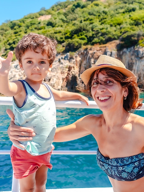 Mother and son waving on a boat near Gremina Beach, Albania.