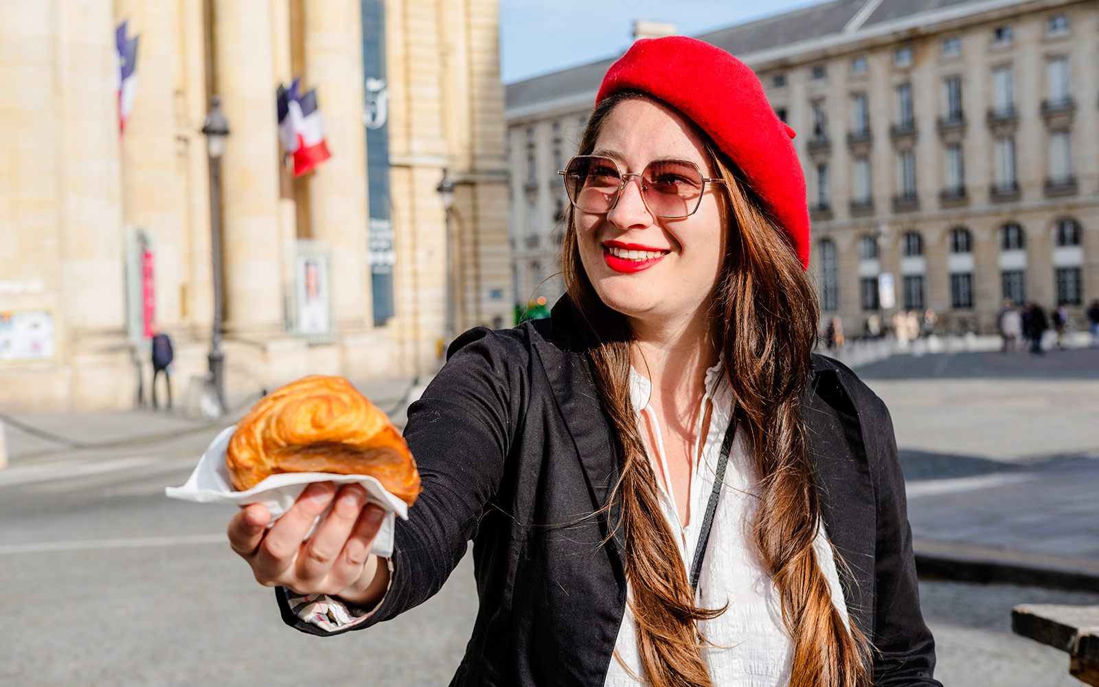 Woman in red beret offering croissant on Emily in Paris Locations Walking Tour.