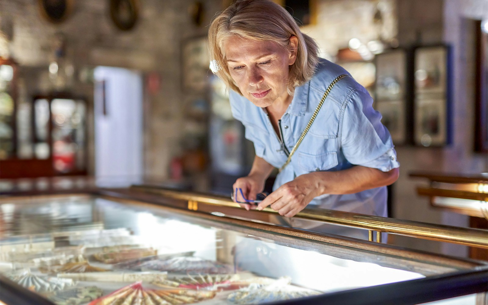 Visitor examining display case at Louvre Museum, Paris.