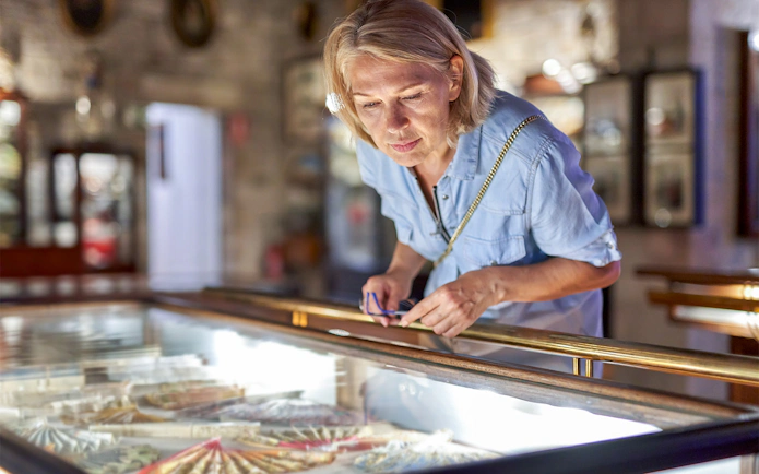 Visitor examining display case at Louvre Museum, Paris.