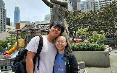 Chinatown park with statue and skyscrapers in San Francisco, part of self-guided city exploration game.