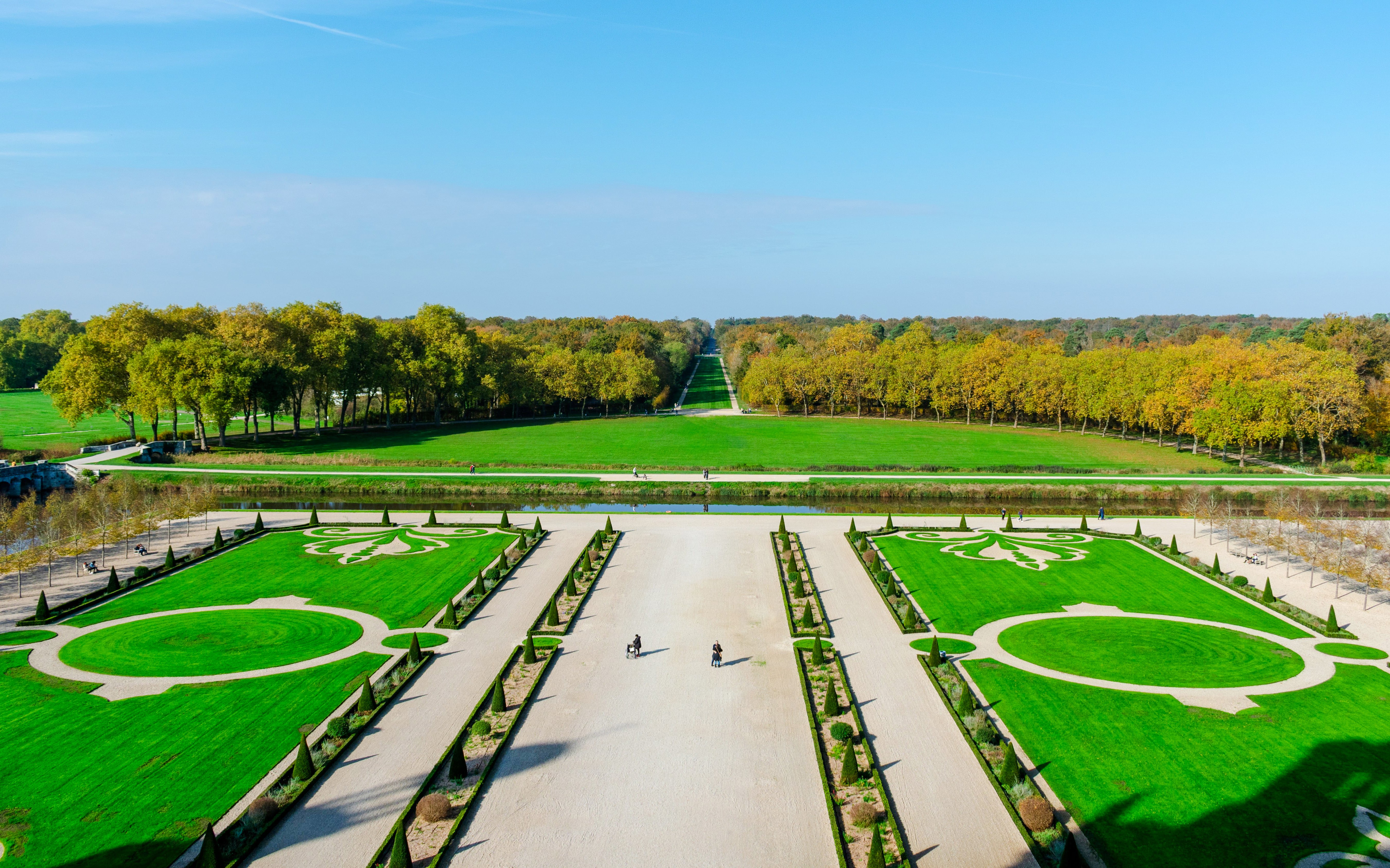 Chambord Castle Gardens with symmetrical lawns and tree-lined pathways in France.
