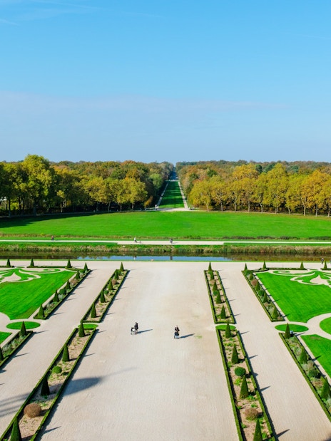 Chambord Castle Gardens with symmetrical lawns and tree-lined pathways in France.