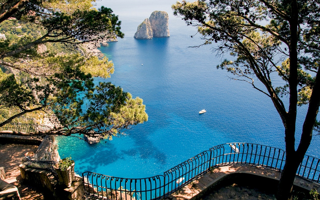 Capri Island coastline view with Faraglioni rocks and blue sea from a scenic overlook.
