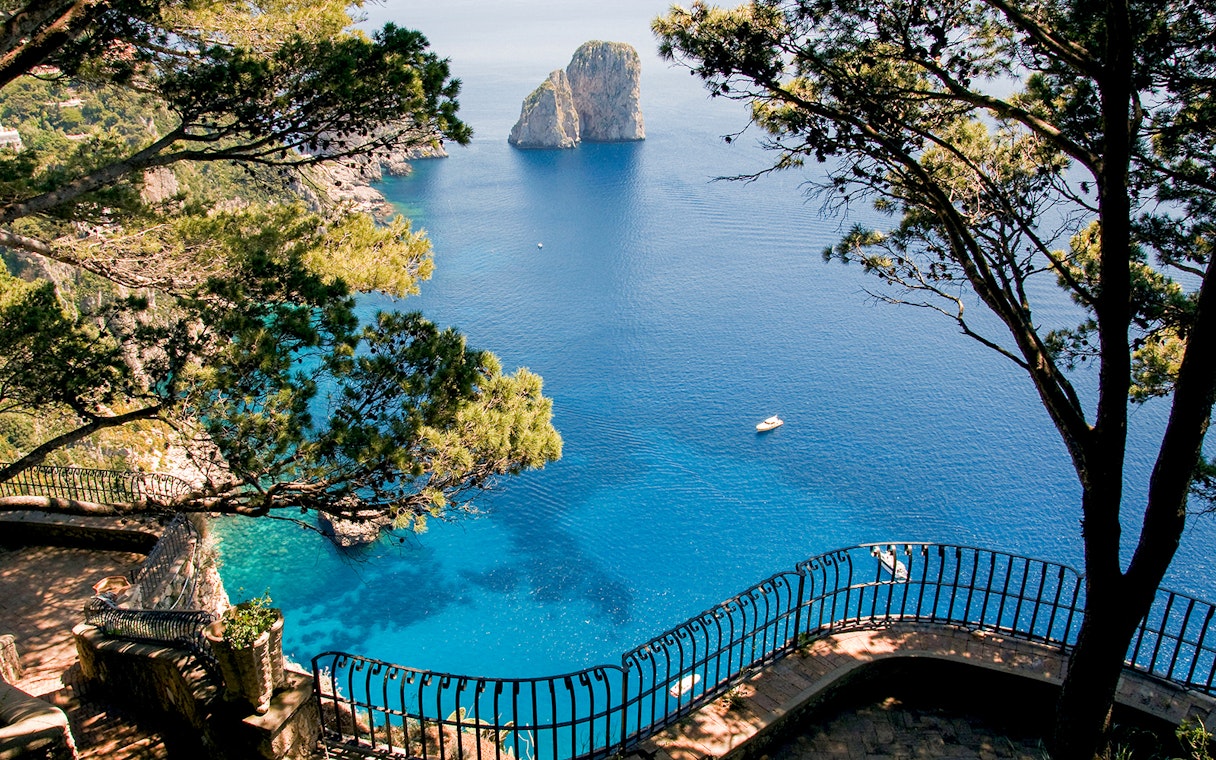 Capri Island coastline view with Faraglioni rocks and blue sea from a scenic overlook.