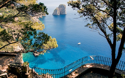 Capri Island coastline view with Faraglioni rocks and blue sea from a scenic overlook.