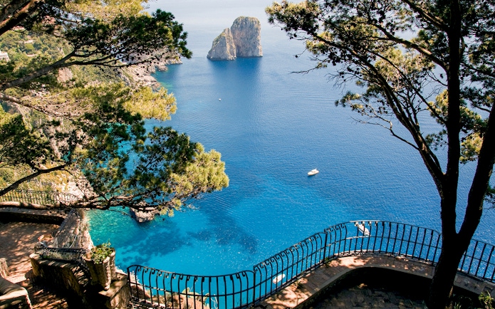 Capri Island coastline view with Faraglioni rocks and blue sea from a scenic overlook.