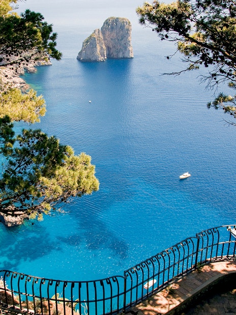 Capri Island coastline view with Faraglioni rocks and blue sea from a scenic overlook.