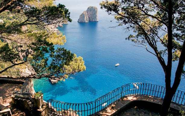 Capri Island coastline view with Faraglioni rocks and blue sea from a scenic overlook.
