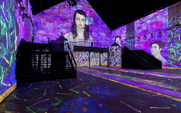 Immersive art projections at Fabrique des Lumières, featuring vibrant portraits on walls.