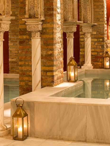 Traditional Hammam Bath interior in Granada with ornate columns and lanterns by the pool.