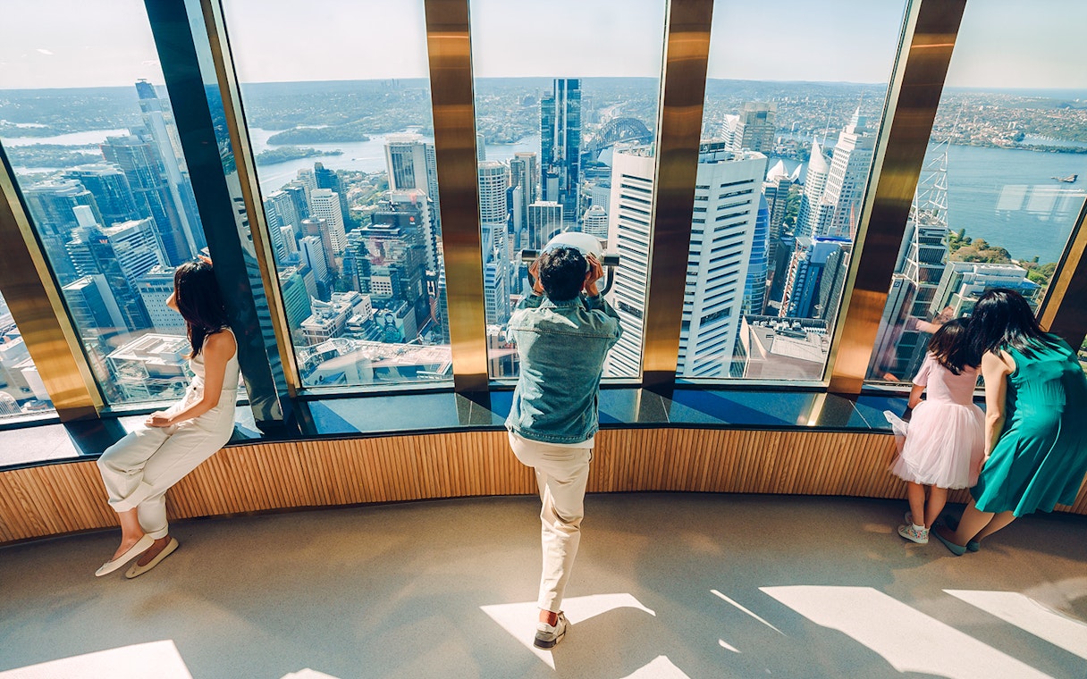 Visitors on Sydney Tower Eye viewing deck overlooking city skyline.