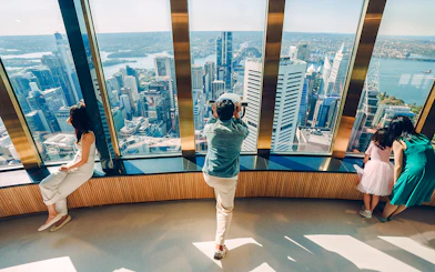 Visitors on Sydney Tower Eye viewing deck overlooking city skyline.