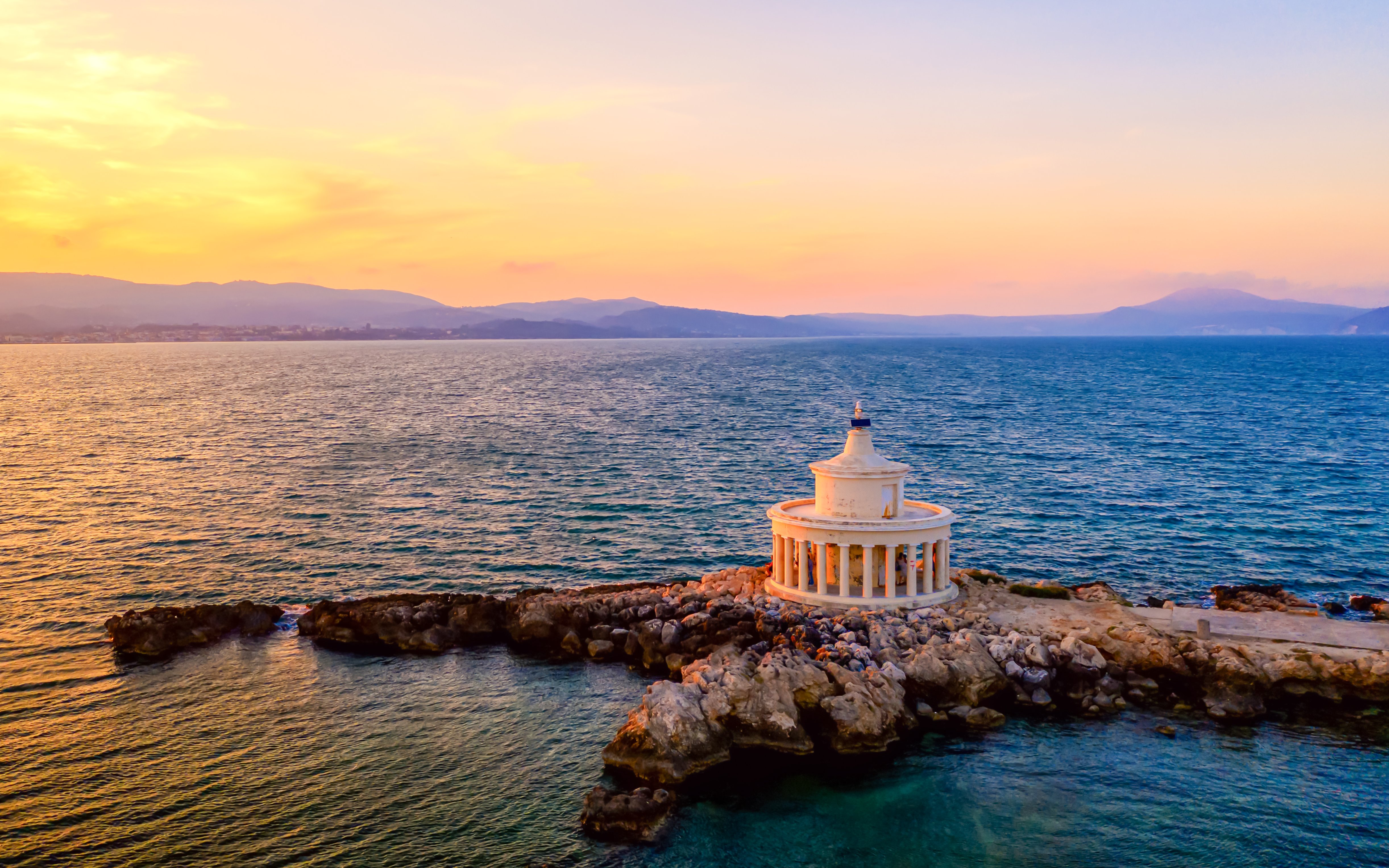 Saint Theodore lighthouse on rocky coast at sunset, Greece.