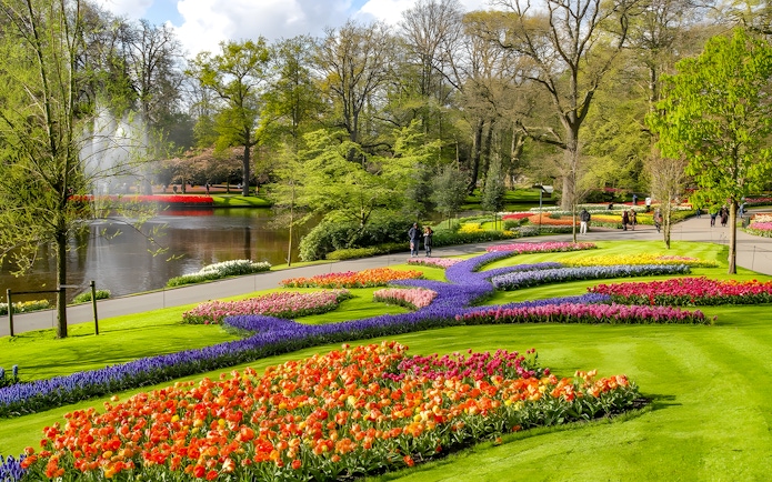 Keukenhof Gardens with colorful tulip beds and a pond, Amsterdam bus tour.