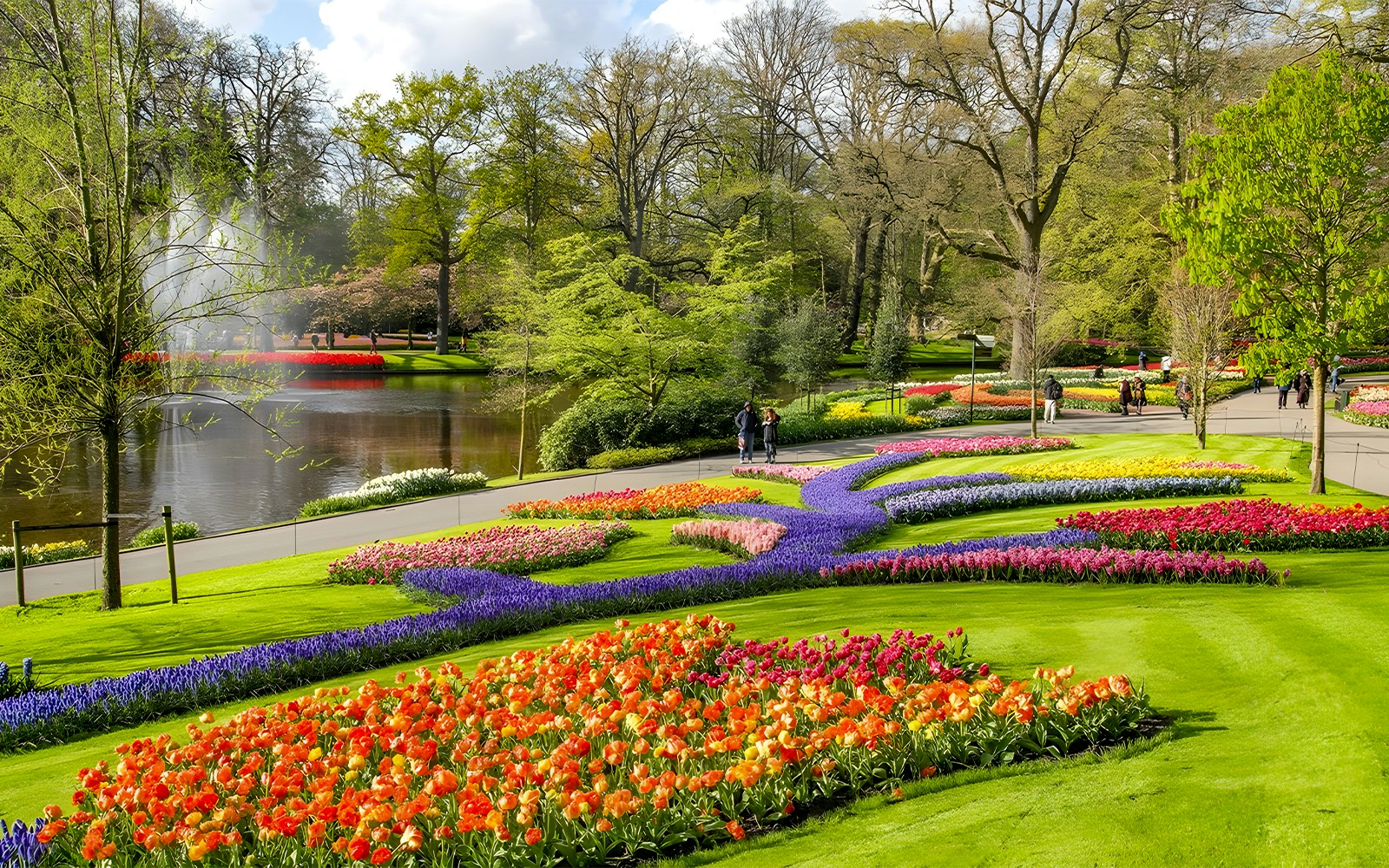 Keukenhof Gardens with colorful tulip beds and a pond, Amsterdam bus tour.