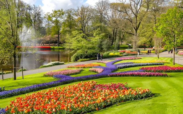 Keukenhof Gardens with colorful tulip beds and a pond, Amsterdam bus tour.