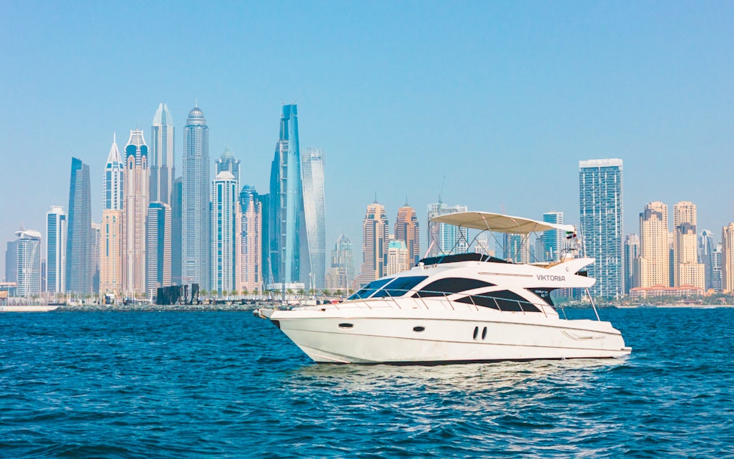 Private luxury yacht sailing in front of Dubai Marina skyline.