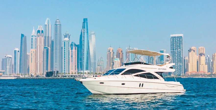 Private luxury yacht sailing in front of Dubai Marina skyline.