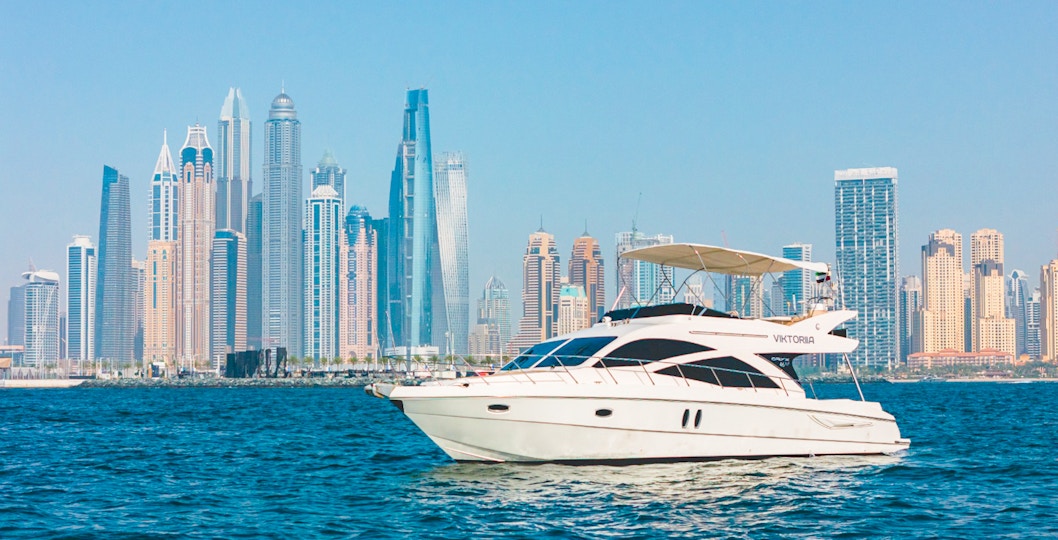 Private luxury yacht sailing in front of Dubai Marina skyline.