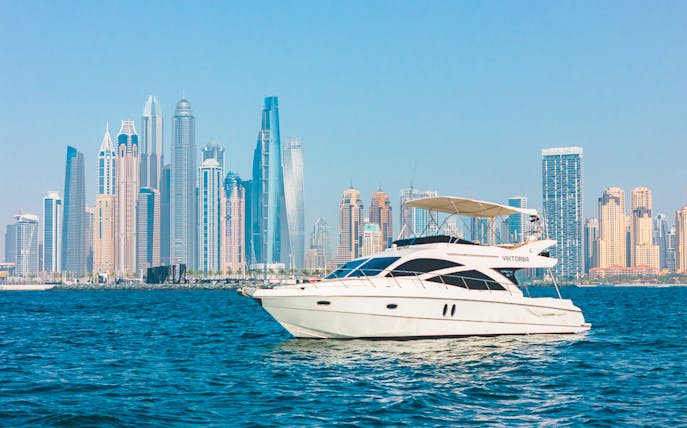 Private luxury yacht sailing in front of Dubai Marina skyline.