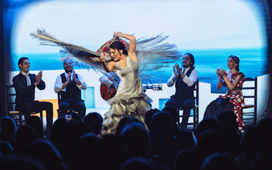Flamenco dancers performing at Teatro Flamenco Barcelona with musicians clapping.