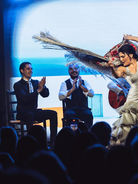 Flamenco dancers performing at Teatro Flamenco Barcelona with musicians clapping.