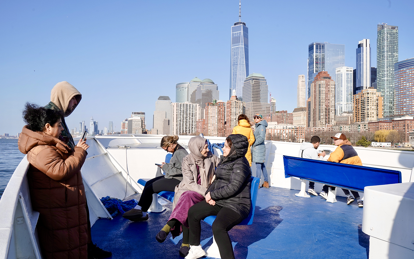 Guests enjoying views of NYC skyline on Statue of Liberty sightseeing cruise.