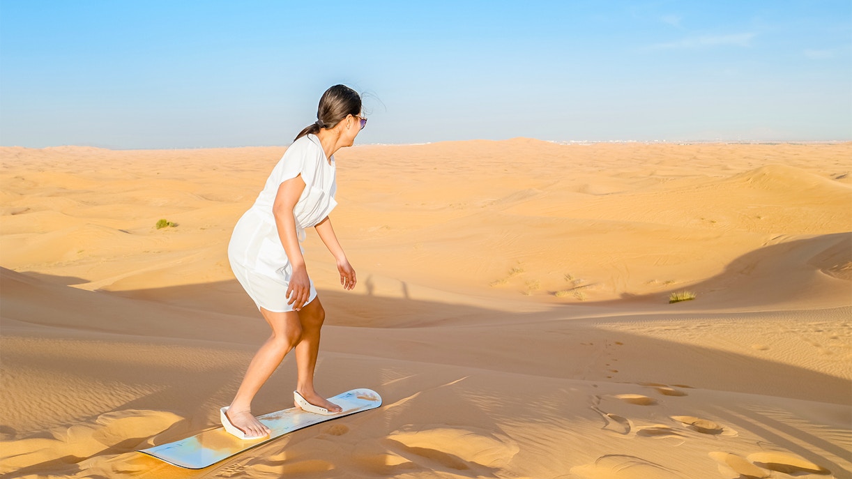 Femme faisant du sandboarding dans le désert