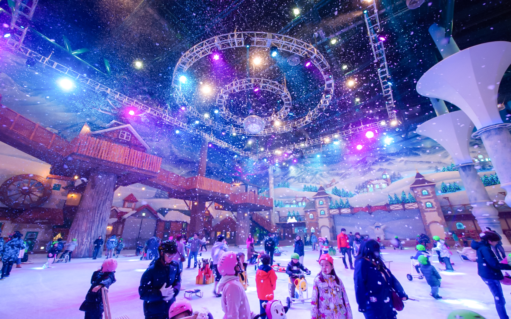 Tourists enjoying indoor winter activities at Vivaldi Park Ski World under colorful lights.
