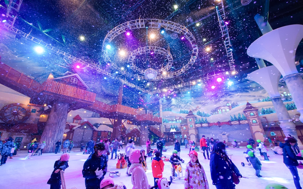 Tourists enjoying indoor winter activities at Vivaldi Park Ski World under colorful lights.