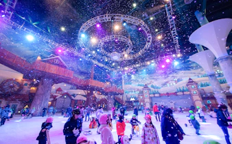 Tourists enjoying indoor winter activities at Vivaldi Park Ski World under colorful lights.
