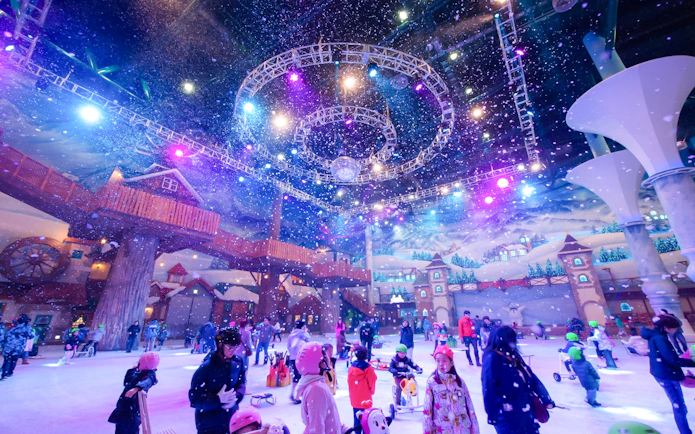Tourists enjoying indoor winter activities at Vivaldi Park Ski World under colorful lights.