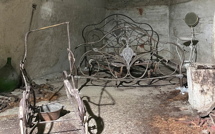 Antique metal bed frame in Naples Underground cave setting.