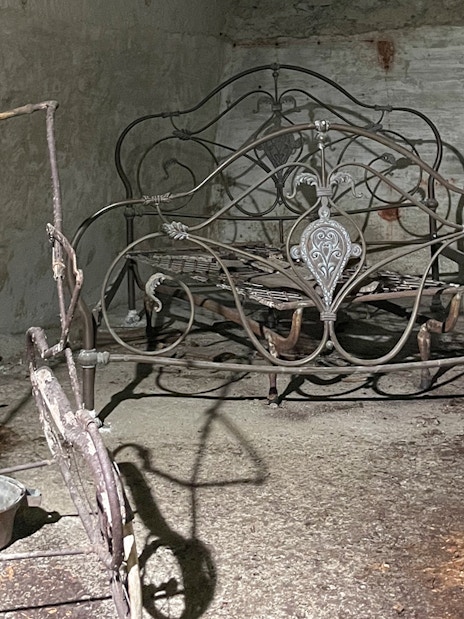 Antique metal bed frame in Naples Underground cave setting.