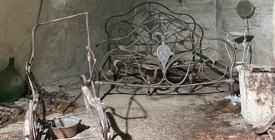 Naples Underground tour showcasing ancient bed frame in historic chamber.