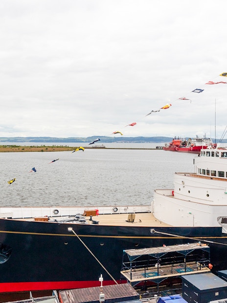 Royal Yacht Britannia docked in Edinburgh with cityscape in the background.