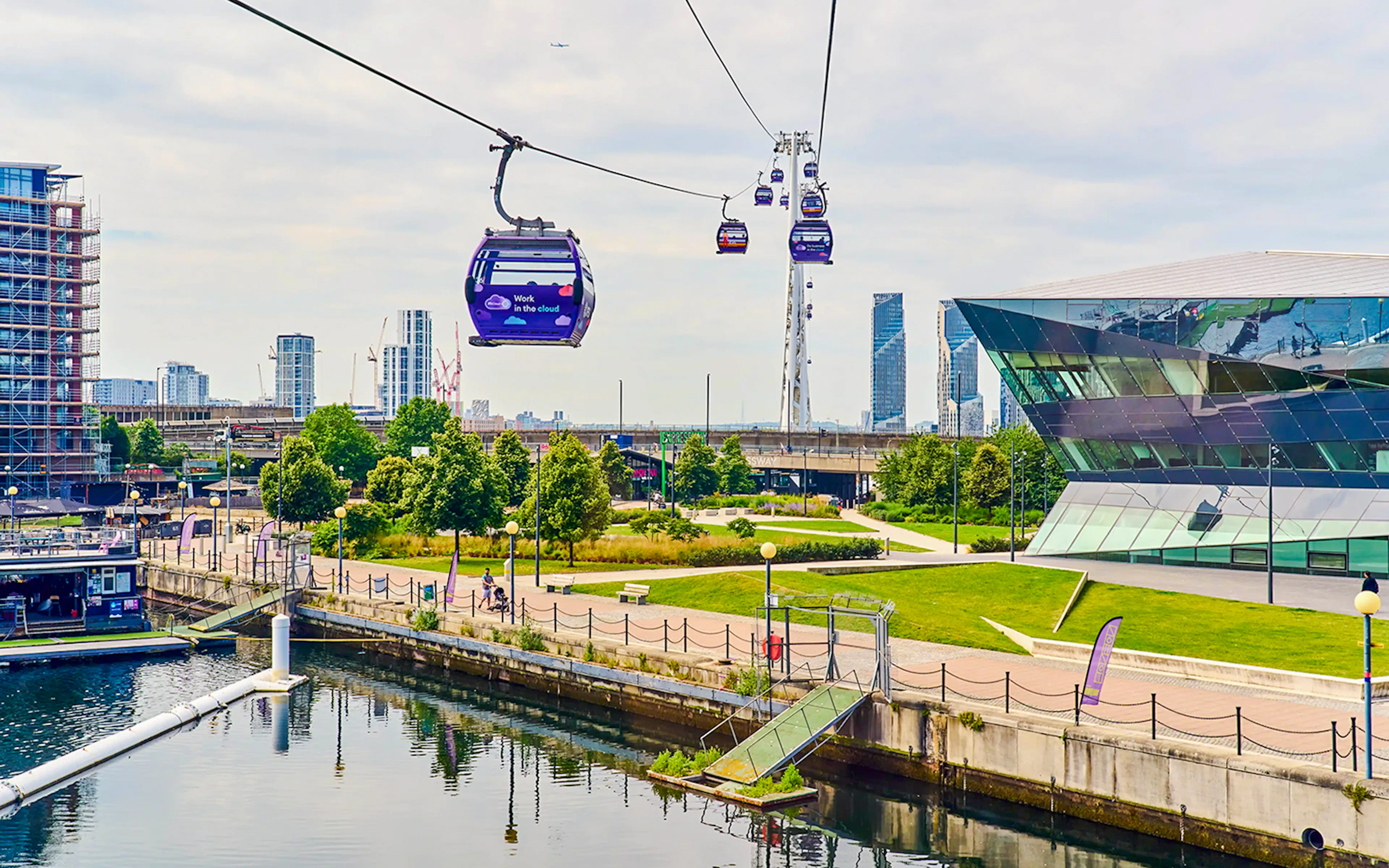 London IFS Cable Cars moving over the Thames with cityscape in the background.