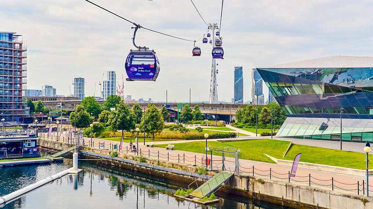 London IFS Cable Cars moving over the Thames with cityscape in the background.
