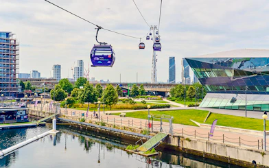 London IFS Cable Cars moving over the Thames with cityscape in the background.