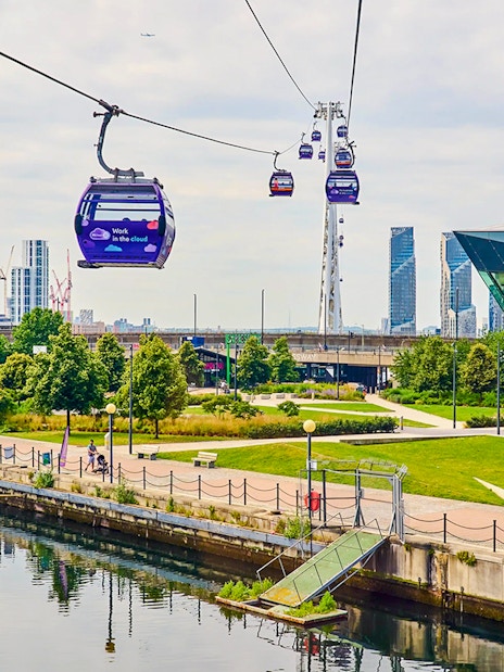 London IFS Cable Cars moving over the Thames with cityscape in the background.