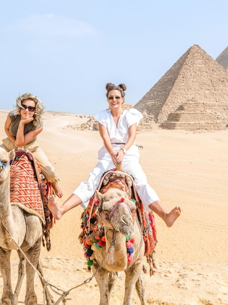 Tourists riding camels near the Giza Pyramids in Egypt.