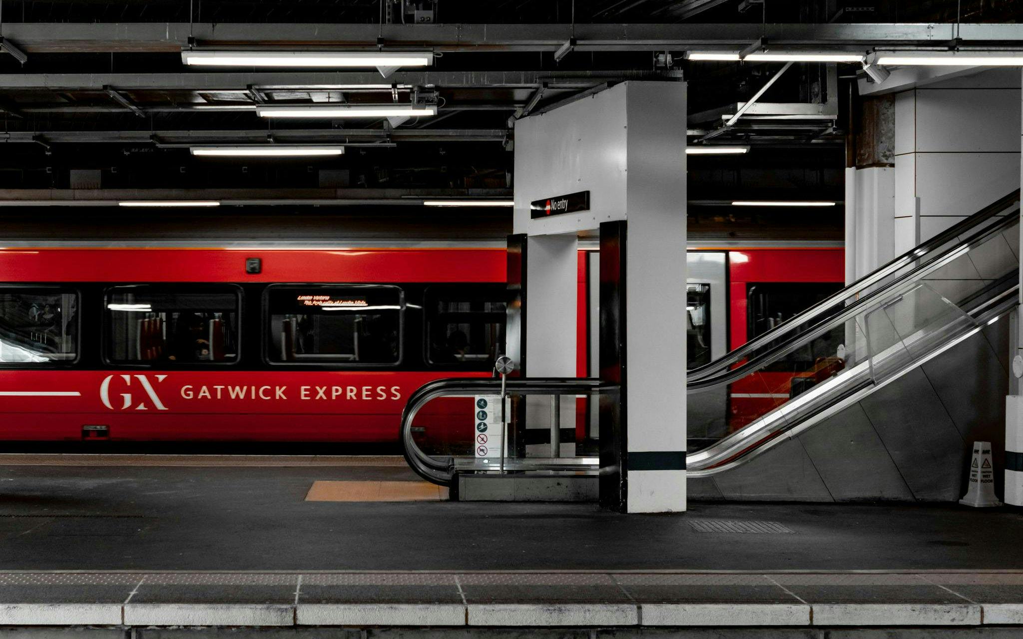 Gatwick Express train at platform with escalator at Gatwick Airport station.