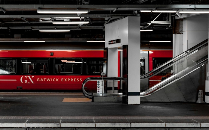 Gatwick Express train at platform with escalator at Gatwick Airport station.