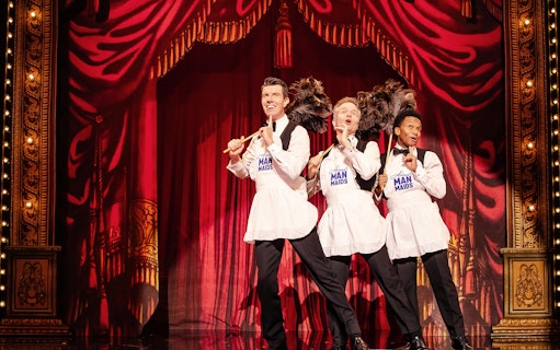 Performers in aprons with feather dusters on stage during Stephen Sondheim's Old Friends show.