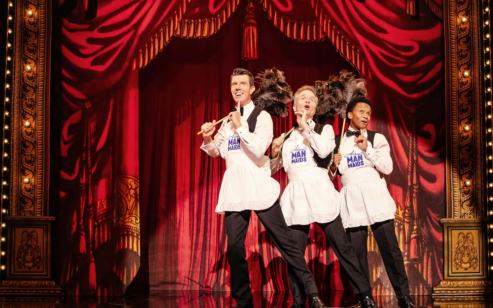 Performers in aprons with feather dusters on stage during Stephen Sondheim's Old Friends show.