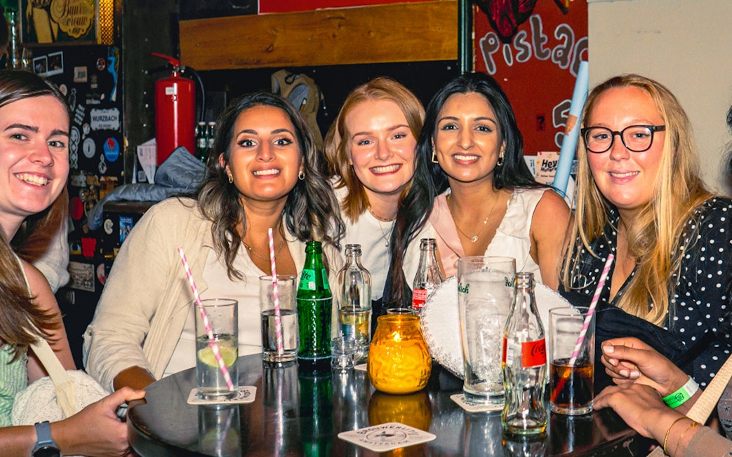 Tourists enjoying drinks at a pub in Amsterdam's Red Light District during a pub crawl.