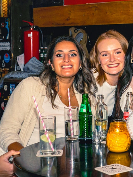 Tourists enjoying drinks at a pub in Amsterdam's Red Light District during a pub crawl.